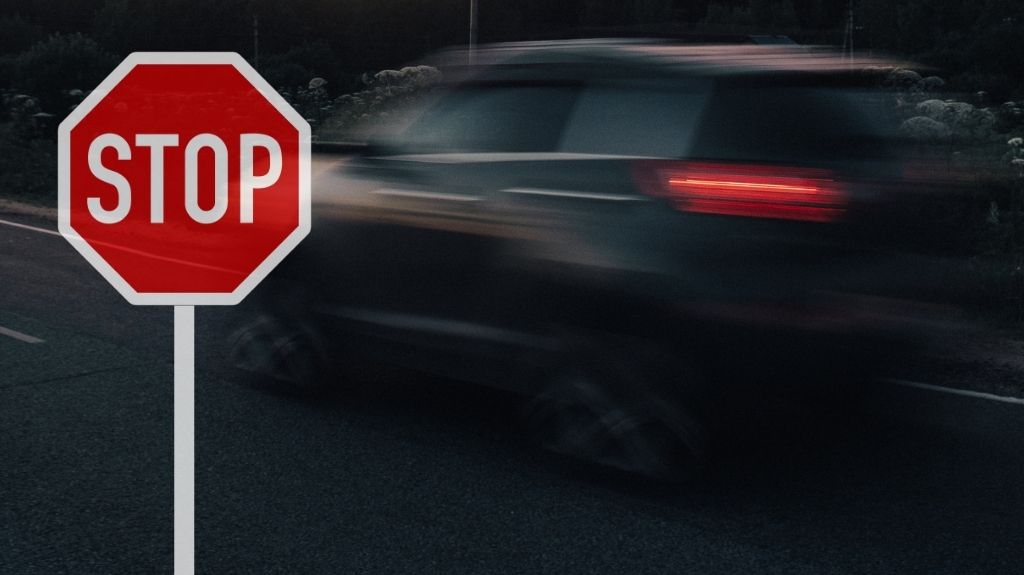 Blurry Car on a Road at Night with Stop Sign